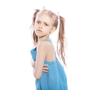 年轻的七岁的黑发女孩在蓝色礼服上的白色孤立的背景。她脸上的愤怒不快悲伤的情绪