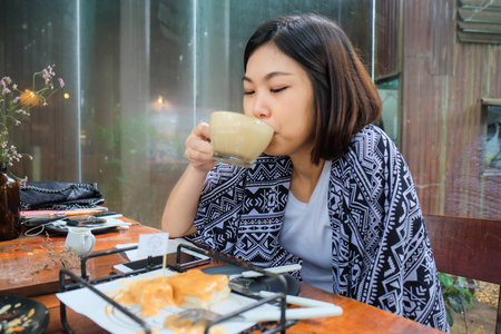 亚洲妇女在艺术咖啡馆 drinkking 拿铁咖啡
