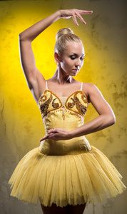 可爱的芭蕾舞女演员在黄色短裙假扮过时的墙上