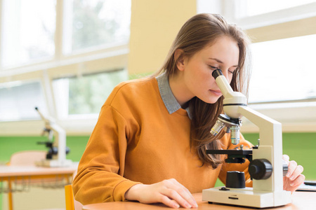 高中女学生在生物类。学生用显微镜检查样品