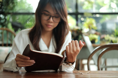 戴眼镜的年轻学生妇女坐在图书馆和 readi