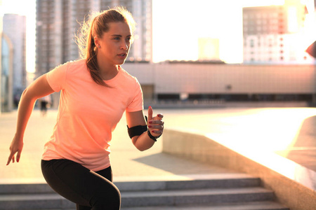 年轻迷人的运动健身妇女运行时, 在户外运动在日落或日出在城市