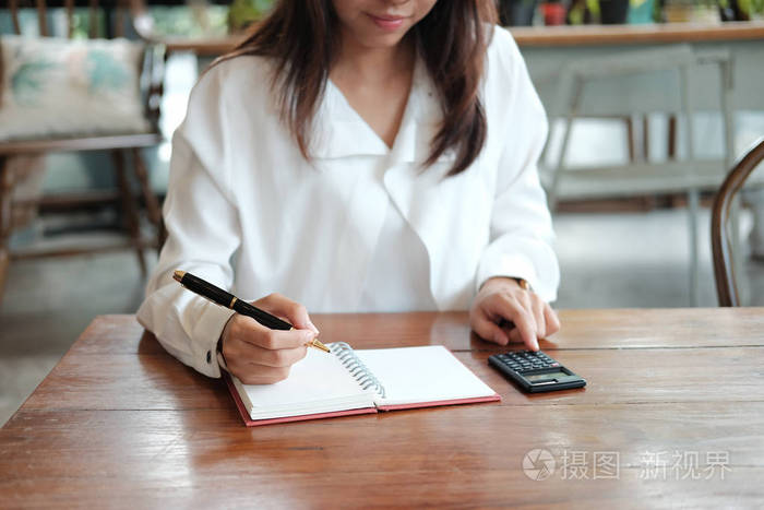 年轻学生妇女拿着笔在笔记本纸上写字照片-正版商用图片0814eq-摄图新
