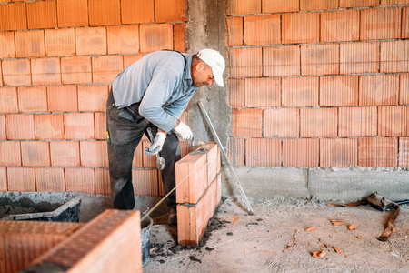 瓦工工业工人用抹灰刀在内墙上安装砖砌体