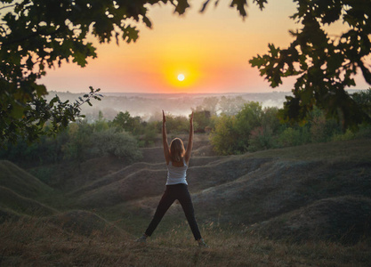 年轻女子在日落时练瑜伽