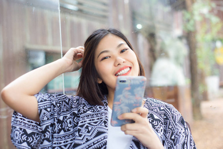 美丽的年轻时髦的亚洲妇女使用应用程序发送手机上的信息在咖啡馆