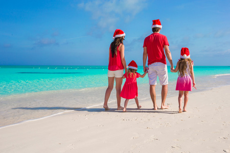 快乐一家四口在白色沙滩上的圣诞帽