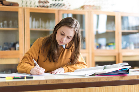 年轻女大学生在化学课上, 写笔记。在课堂上有重点的学生。地道的教育理念