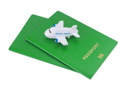 白色背景上绿色护照上面的小玩具飞机