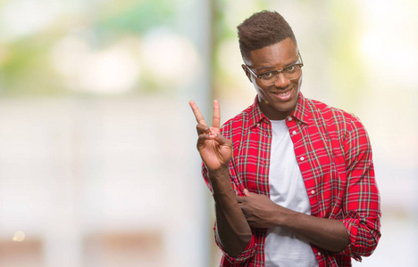 年轻的非洲裔美国人在孤独的背景微笑着愉快的脸眨眨眼在相机做胜利标志。第二个