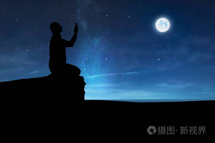 穆斯林男子举手和夜间祈祷剪影