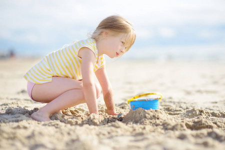 可爱的小女孩在沙滩上享受温暖和阳光明媚的夏日乐趣。在海边玩耍的孩子。儿童暑期活动