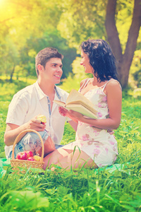 快乐的年轻夫妇，坐在草笑着说