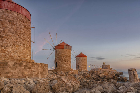 在历史悠久的希腊岛屿上的罗德镇的圣尼古拉斯城堡和风车的长曝光照片
