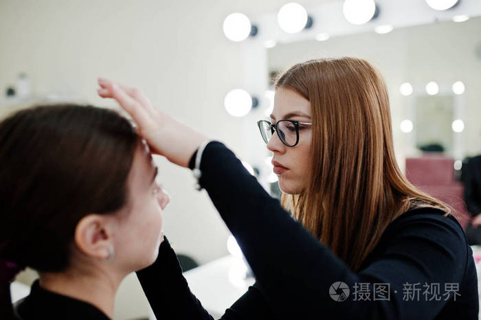 化妆师工作在她的美容美发工作室沙龙.女性应用程序