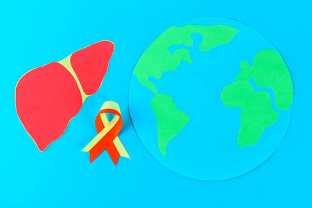 世界肝炎日。6月28日。蓝桌上的红黄丝带地球和肝脏