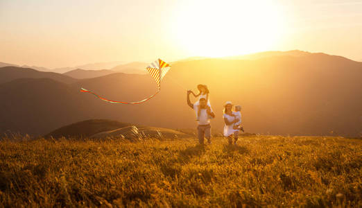 快乐的家庭父亲, 母亲和孩子们在孙子的大自然中推出风筝。