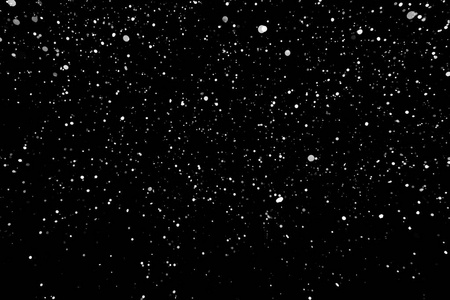 暴风雪的纹理。在黑色背景上的散景灯拍摄的飞片雪花在空中
