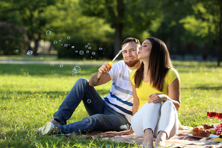 快乐的情侣吹肥皂气泡在公园的春天天