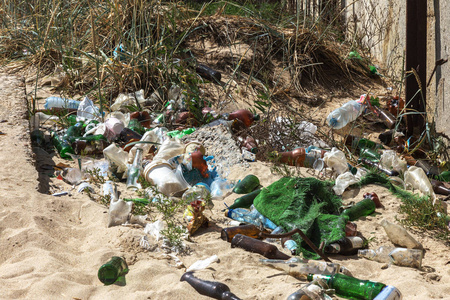 在大城市的海滩上洒下垃圾。空用的脏塑料瓶。肮脏的海沙岸黑海。环境污染。生态问题。公共海滩围栏附近的垃圾转储