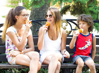 儿童小组在夏季城市的长凳上吃冰淇淋