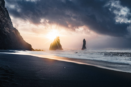 在冰岛著名的黑色沙滩 Reynisfjara 日出。刮风的早晨。海浪。五彩缤纷的天空。早晨日落