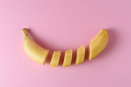 切片香蕉在柔和的粉红色背景。最小水果概念