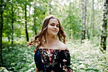 一个神话般的年轻女孩在漂亮的礼服与时尚的卷发发型摆在森林或公园的肖像