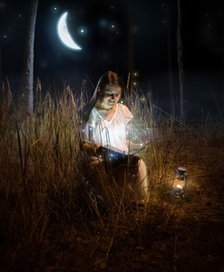 美丽的女人坐在夜森林和阅读童话故事 b