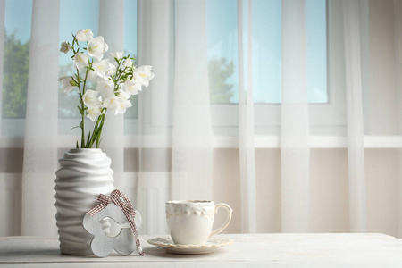 花钟在花瓶里, 一杯茶放在窗前的木桌上。复制空间