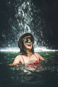 在深丛林与瀑布微笑的年轻妇女游客。真正的冒险概念。巴厘岛