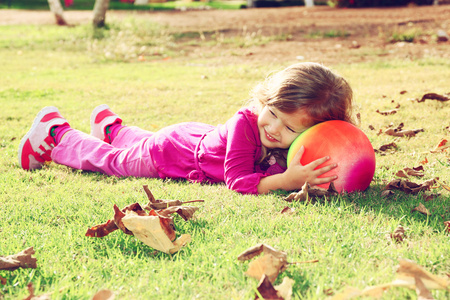 玩球，她在公园的草地上的小的可爱的女孩。已过滤的图像