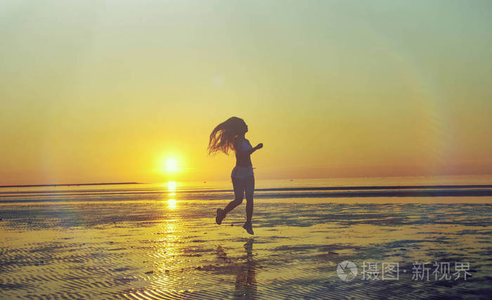 夕阳下海边的女孩的剪影日落黑海滩背景与太阳夏季女子健身运动活动
