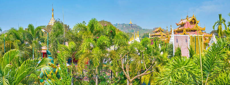 神社的屋顶和主宝塔的顶部仅在缅甸曼德勒 Kyauktawgyi 宝塔花园的郁郁葱葱的绿地上可见。