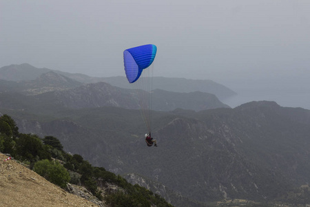 一个在降落伞上的人正在飞越群山。Parasailin