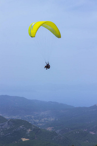 一个在降落伞上的人正在飞越群山。Parasailin