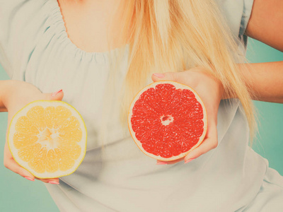 健康的饮食，刷新富含维生素的食物。女人抱着甜美味的柑橘水果，红色和绿色的葡萄柚