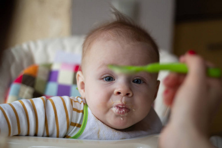 婴儿的第一次从勺子喂婴儿。妈妈用勺子喂婴儿均质切碎的食物。儿童保育