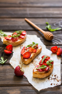 意大利 bruschetta 奶油芝士, 草莓, 芝麻菜和香醋酱和蜂蜜。在木质背景下 chiabatta 面包和草莓的开胃菜。意