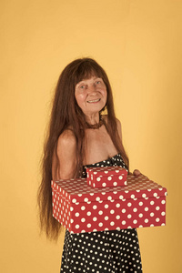 老妇人与礼物。长红色头发的妇女举行五颜六色的箱子