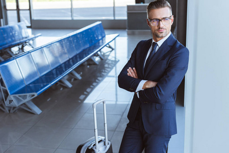 商人戴眼镜站在机场候机室带着行李
