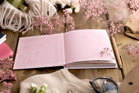打开笔记本和粉红色的花朵在一个木质的背景。卡. 文本的可用空间。复制空间