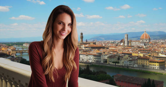 在佛罗伦萨的微笑的妇女放松在外面与城市景观