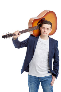 特写一个年轻的家伙站在一个蓝色夹克的声学吉他。在白色背景上被隔离