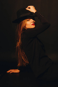 一个年轻的白种女人的肖像在黑暗的工作室帽子