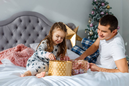 家庭在家里度过空闲时间。愉快的家庭在床上与女儿一起玩。在圣诞节和新年前夕