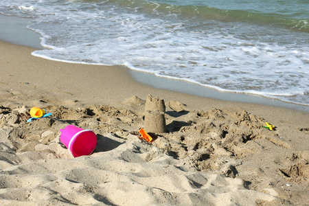 沙滩上的沙子城堡。海滩上的儿童玩具。暑假