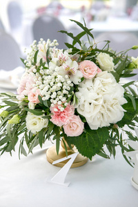 美丽的白色餐桌, 为客人装饰着绿色和长布。花安排的绣球花, 玫瑰, 果蝇, 百合花和绿叶在桌子上的数字
