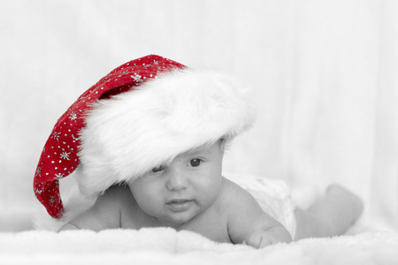 可爱刚出生的婴儿躺在白色背景上的红色圣诞帽