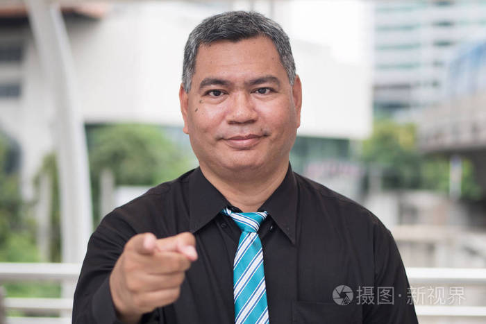 自信 成功的亚洲商人的肖像手指或指向手在相机;50s 旧东南亚人模型